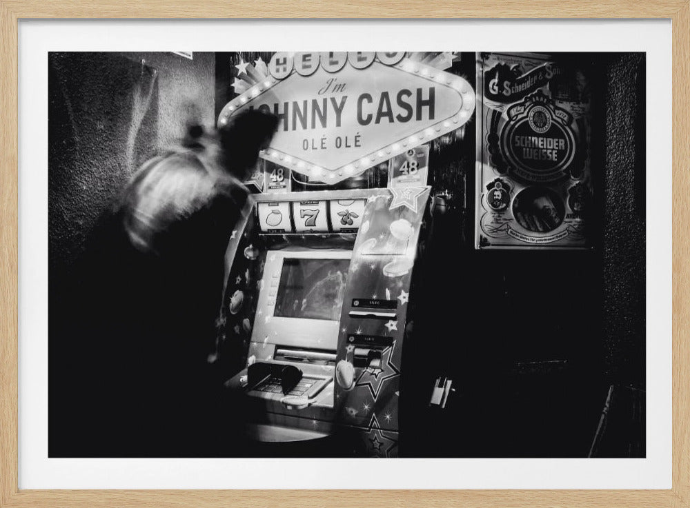 A grainy, black and white photograph of a person blurred by motion standing in front of a Johnny Cash themed slot machine. A lit marquee sign above the machine reads "HELLO I'm JOHNNY CASH OLÉ OLÉ". The setting appears to be a dark bar or casino. Wall Art