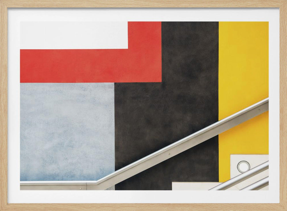 A framed abstract art piece featuring a composition of large, solid-colored geometric shapes in red, yellow, black, white, and light gray. A silver handrail cuts diagonally across the lower portion of the image, adding a sharp line and a sense of architectural space. Artwork