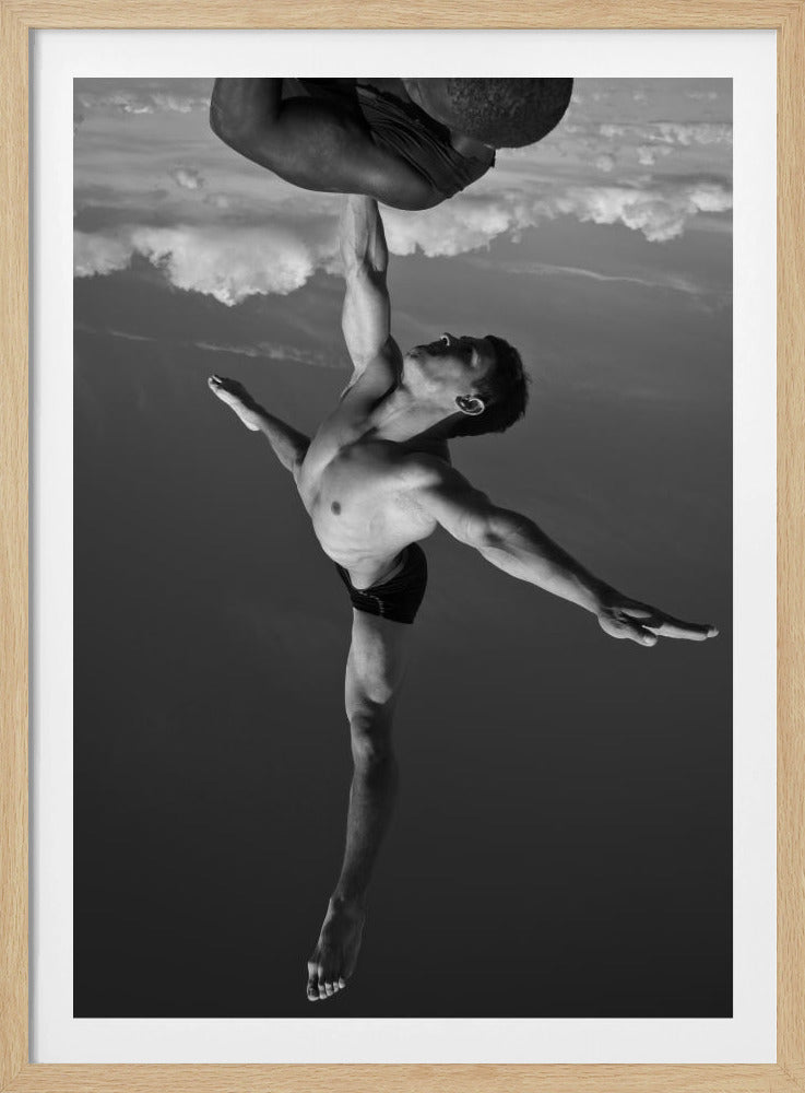 A surreal black and white photograph of two male acrobats. One man, in a graceful dance-like pose balancing on one leg, holds another man aloft with a single outstretched arm. The man being held is upside down against a backdrop of clouds, creating a gravity-defying and artistic illusion. Print