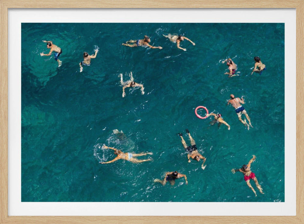 An aerial top-down photograph of a group of people swimming in vibrant turquoise ocean water, captured within a silver frame. Print