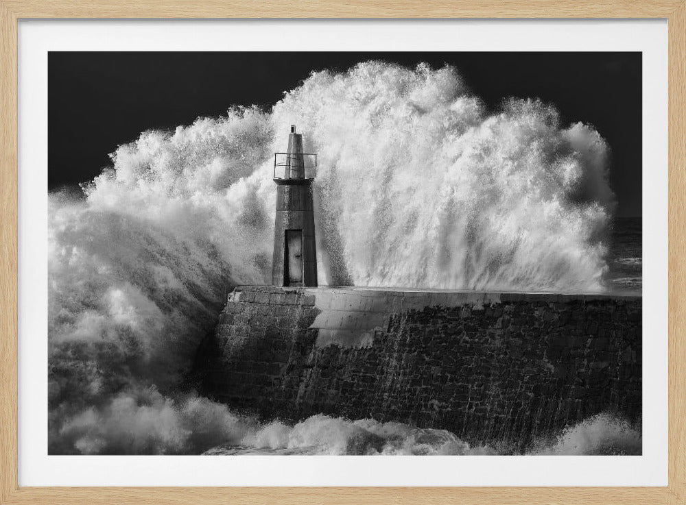 A dramatic black and white photograph of a massive wave crashing against a stone pier and a small lighthouse. The white foam of the wave towers over the structure, creating a powerful and dynamic scene against a dark sky, all enclosed in a silver frame. Poster