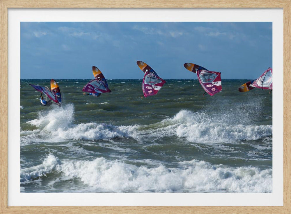 A composite, silver-framed photograph capturing the four stages of a windsurfer's impressive jump over choppy, white-capped ocean waves under a partly cloudy blue sky. Print
