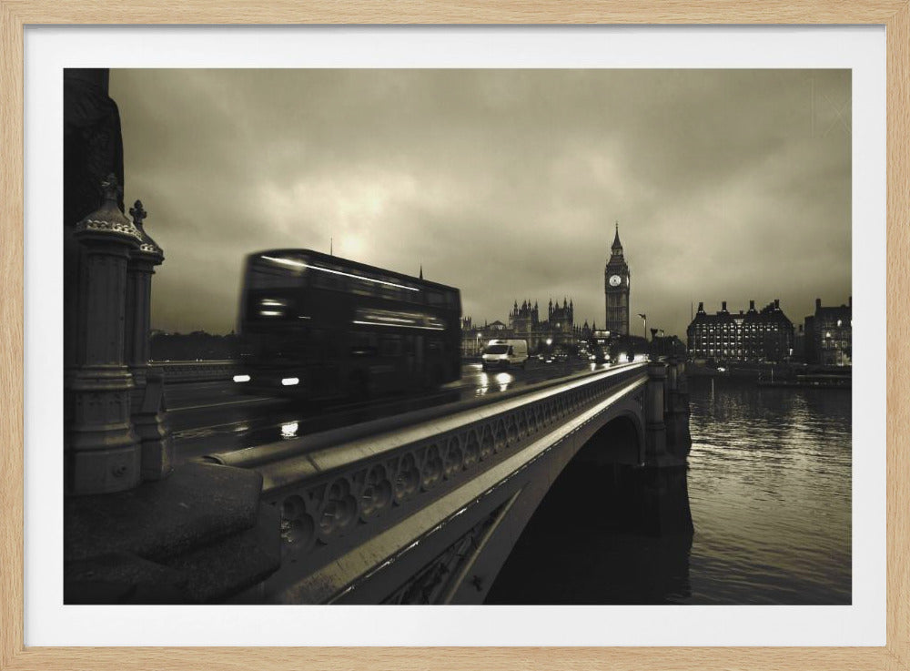 A framed, sepia-toned long-exposure photograph of London. A double-decker bus is shown in motion blur as it crosses Westminster Bridge. In the background, the Big Ben clock tower and the Houses of Parliament are visible against a cloudy sky, with lights reflecting on the wet road and the River Thames. Wall Art