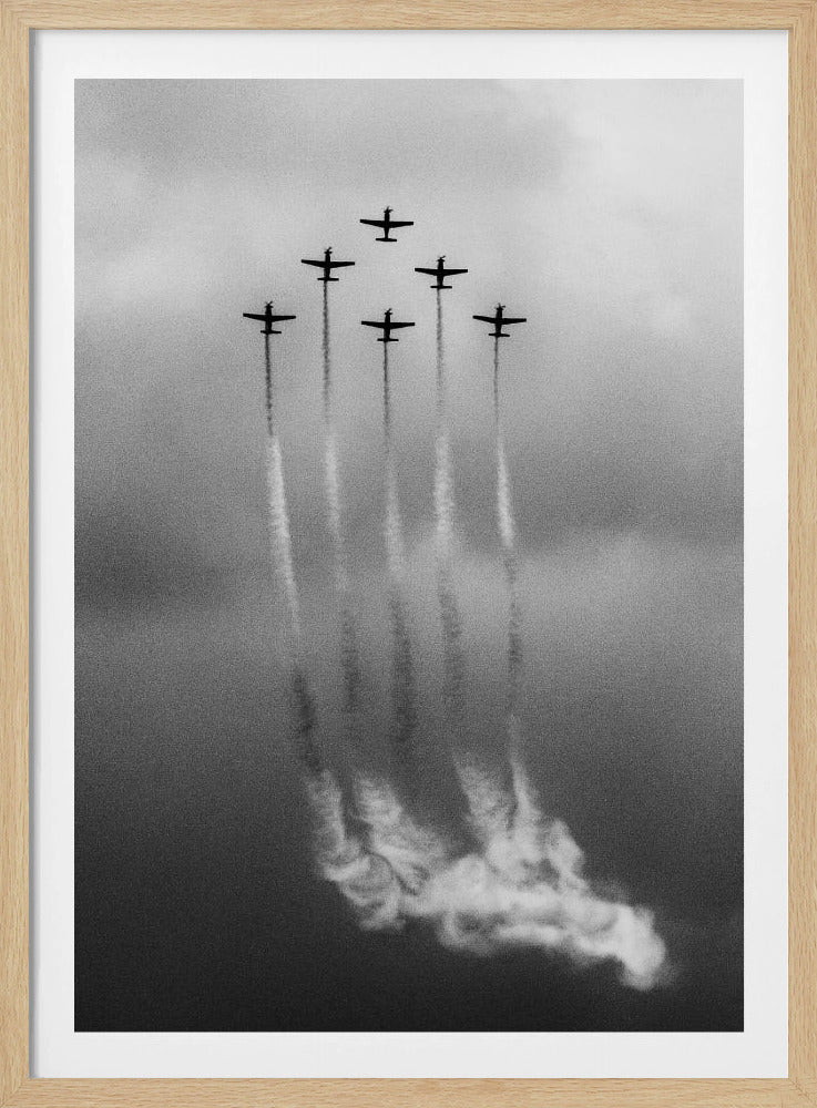 A grainy black and white photo of six airplanes flying in a V-formation against a cloudy sky. Each plane leaves a long, white smoke trail that billows at the bottom of the frame. The image is presented within a black border. Print