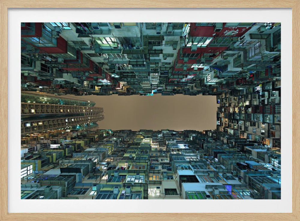 A framed, low-angle photograph looking up from a courtyard at densely packed, colorful apartment buildings that form a rectangle around a blank, overcast sky at night. Print