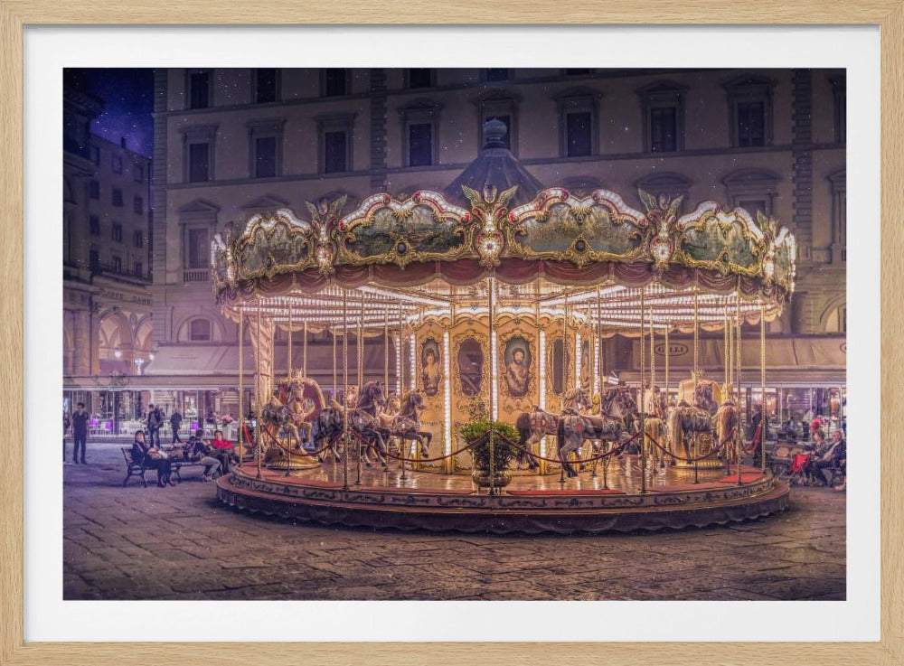 A beautifully illuminated vintage carousel with ornate horses in a European cobblestone plaza at night. The carousel is the central focus, glowing with warm lights against a backdrop of historic buildings and a starry purple sky. Poster