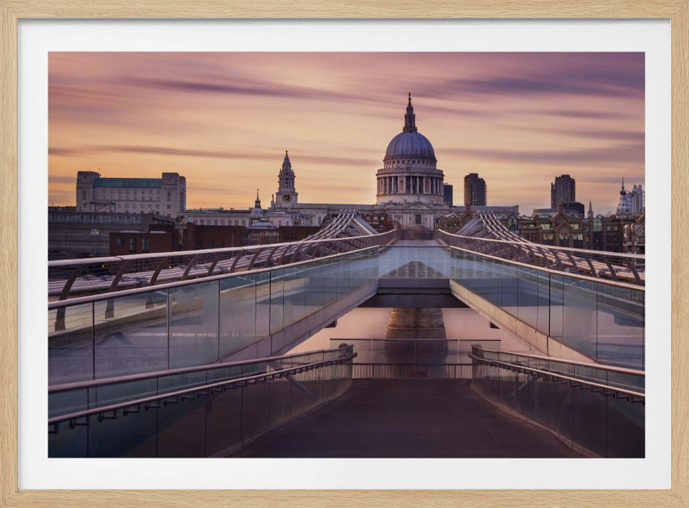A photograph looking down the center of the Millennium Bridge in London, leading the eye directly to St. Paul's Cathedral, which is centered in the background under a beautiful purple and orange sunset sky. Print