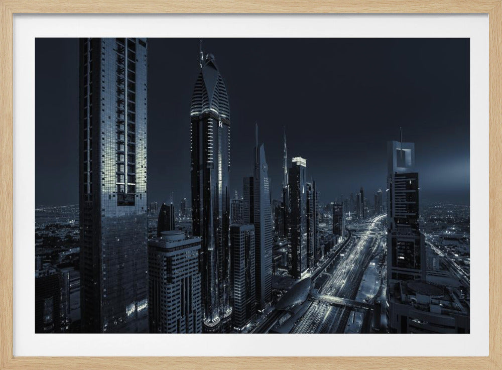 A framed, blue-toned nighttime photograph of a futuristic city skyline from an elevated perspective, featuring illuminated skyscrapers and light trails from traffic on a major highway stretching into the distance. Poster