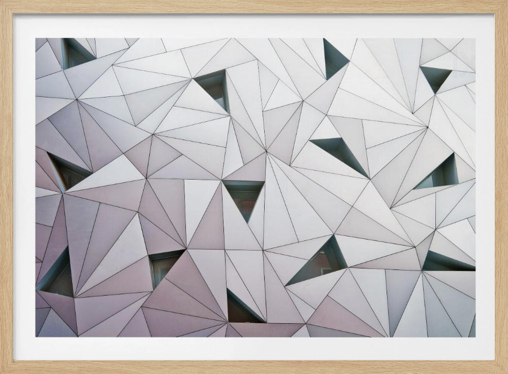 A framed, close-up photograph of a modern building's facade, featuring a complex geometric pattern of interlocking white and light gray triangular panels outlined in black. Some triangles are recessed, creating depth and shadow, hinting at windows. Poster