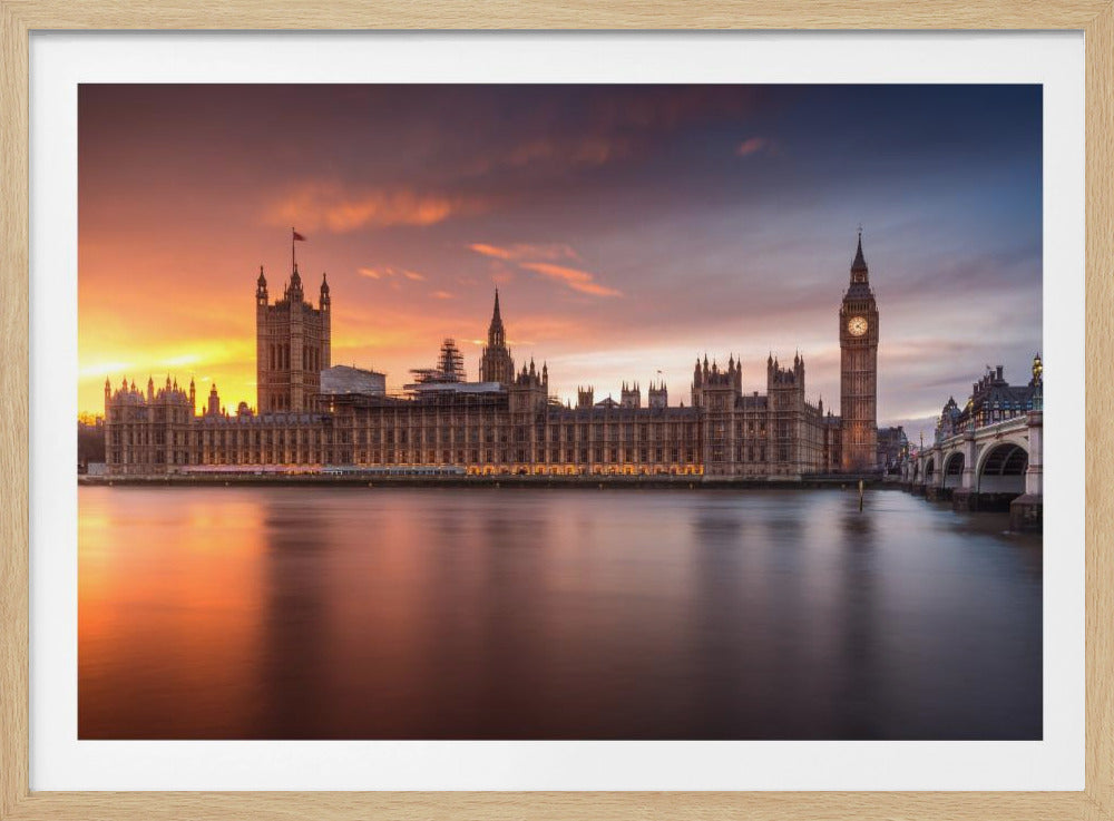 A framed photograph of the Houses of Parliament and Big Ben in London at sunset, with a dramatic orange and purple sky reflecting in the calm waters of the River Thames. Artwork