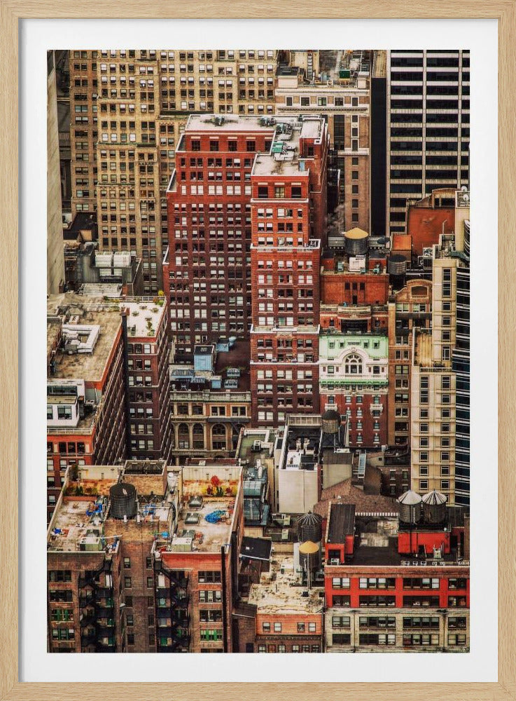 A high-angle, telephoto view of a dense cluster of New York City buildings, featuring a mix of red and brown brick architecture, with numerous windows creating a geometric pattern and several classic wooden water towers perched on the rooftops. Print