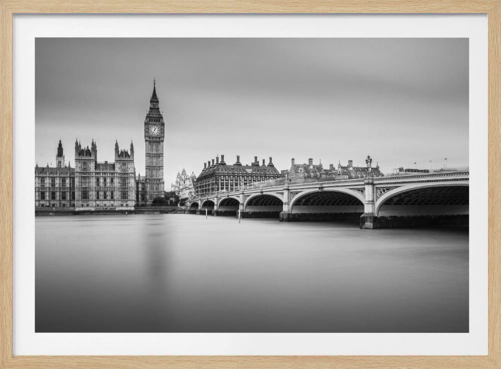 A black and white long-exposure photograph of the Elizabeth Tower (Big Ben) and the Houses of Parliament in London, viewed from across the River Thames. Westminster Bridge stretches across the frame over the smooth, milky water. The image is presented in a silver frame. Artwork