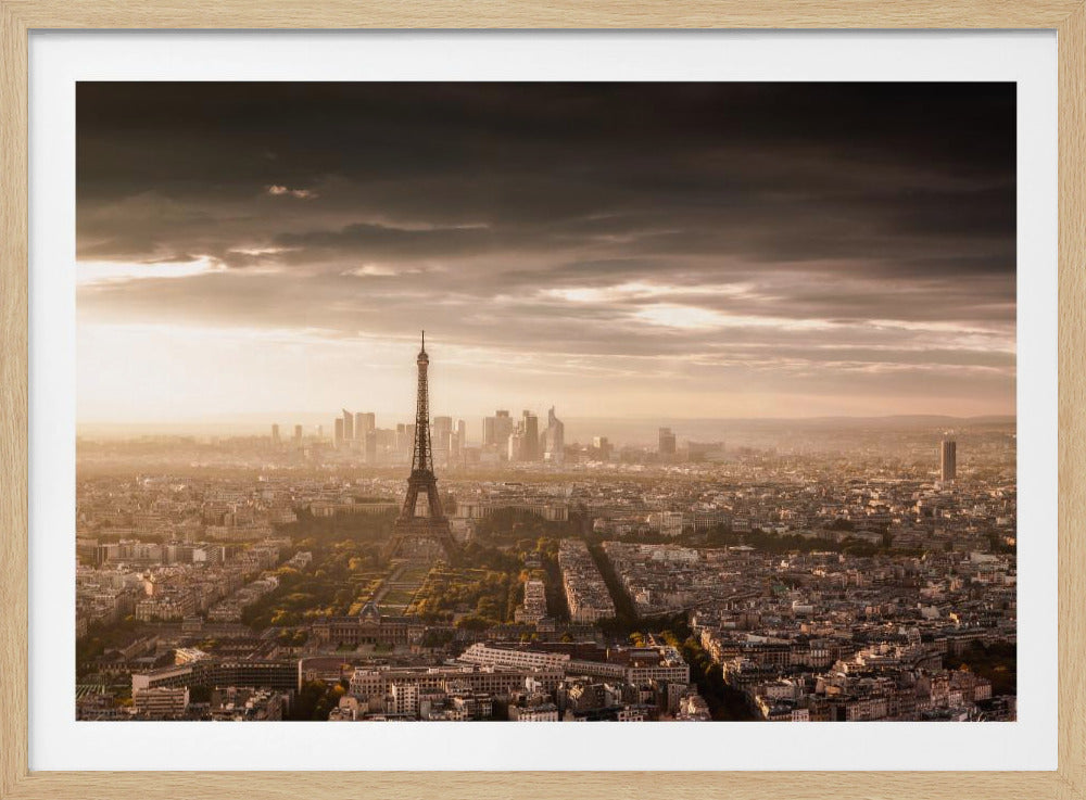 A framed panoramic photograph of Paris at sunrise or sunset, featuring the Eiffel Tower prominently amidst the sprawling cityscape, under a dramatic, cloudy sky illuminated by golden light. Print