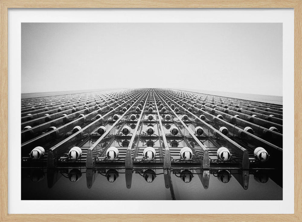 A dramatic low-angle, black and white photograph of a skyscraper's facade. Countless rows of lights on vertical tracks create a strong vanishing point perspective against a bright white sky, emphasizing pattern and scale. Artwork