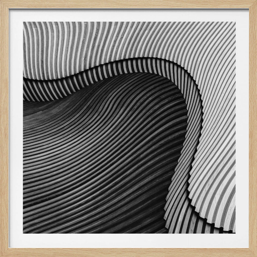 A square, black and white abstract photograph in a light wood frame. The image features layers of flowing, curved surfaces with parallel grooves, creating a strong sense of texture and depth. Lighter, striped layers with vertical lines curve over a darker, undulating section, resembling waves or sculpted wood, drawing the eye into a central dark crevice. Decor