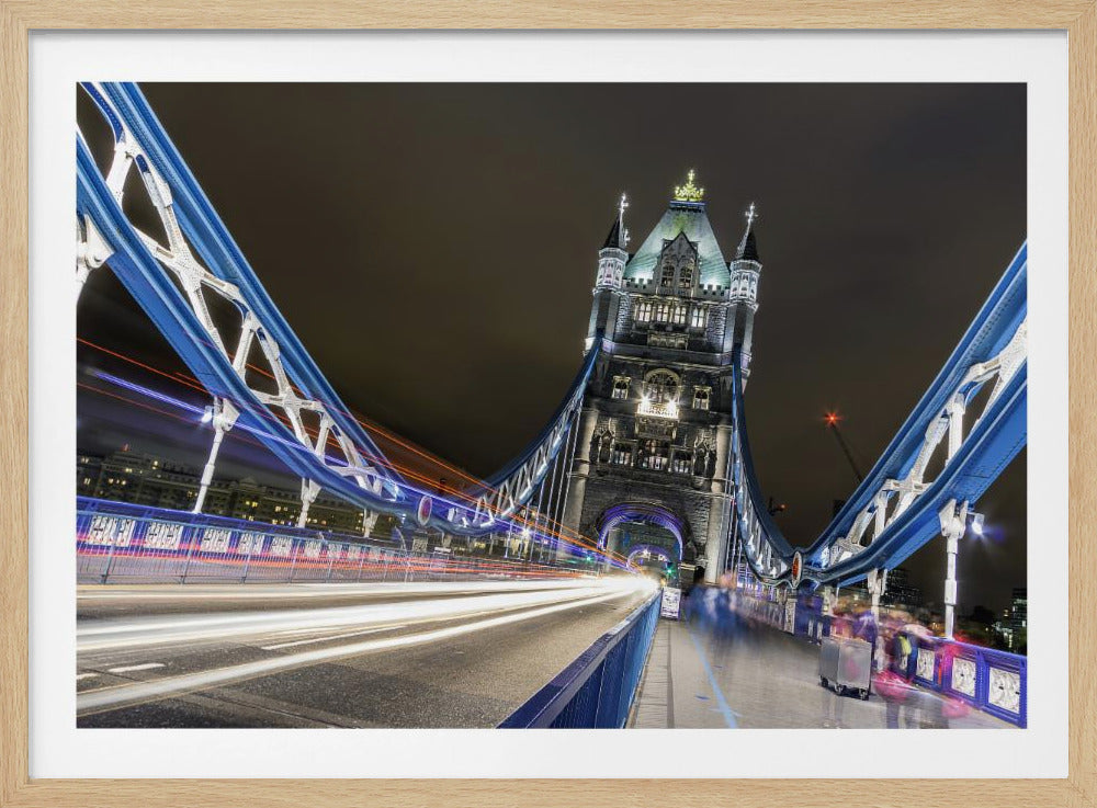 A dramatic, long-exposure night photograph from the deck of London's Tower Bridge, showing vibrant blue support structures curving towards an illuminated stone tower against a dark sky, with bright streaks of light from traffic. Wall Art