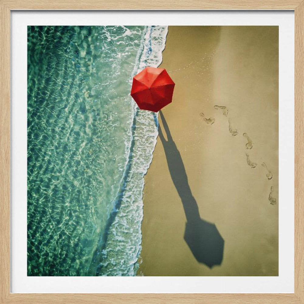 An aerial photograph of a serene beach scene, featuring a vibrant red umbrella on the golden sand next to the clear turquoise ocean. Gentle white waves lap the shore, and a long shadow from the umbrella stretches across the sand, where a trail of footprints leads away. Poster
