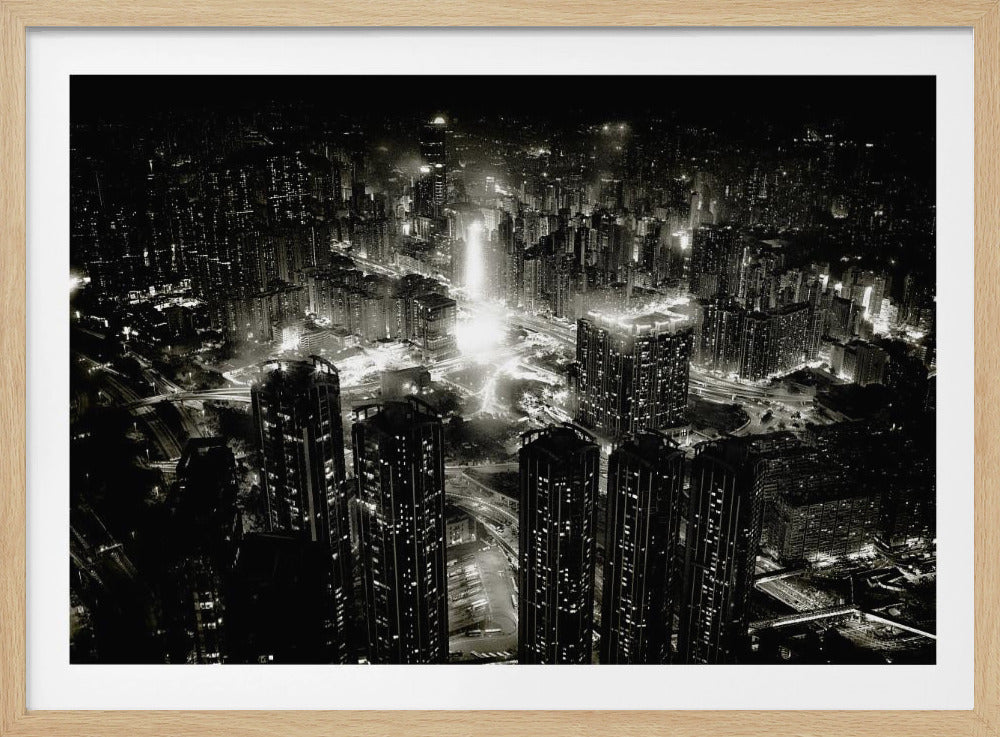 A framed black and white aerial photograph of a dense city at night. The high-angle view captures countless illuminated skyscrapers and winding highways, creating a dramatic and bustling urban landscape. Print