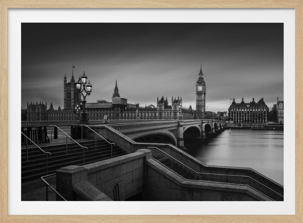 A framed, black and white, long-exposure photograph of the London skyline featuring the Houses of Parliament and the Big Ben clock tower across the River Thames. In the foreground, stone steps lead down towards Westminster Bridge, and the water of the river is smooth and reflective under a dark, cloudy sky. Print