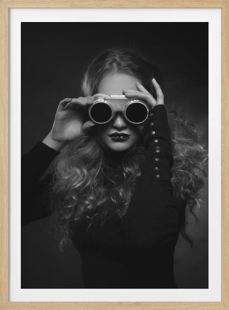 A striking black and white portrait of a woman with long, curly hair holding vintage goggles over her eyes. Her lips are dark and glittery, adding to the mysterious and stylish aesthetic. Print