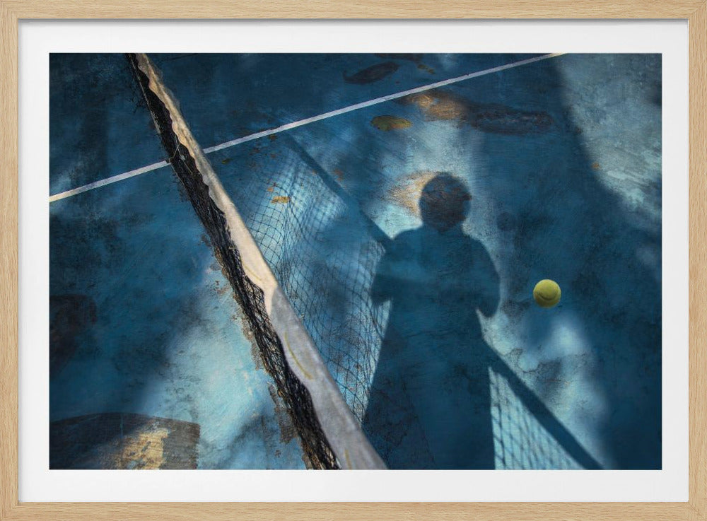 An artistic, high-angle shot of a weathered blue tennis court. The shadow of a tennis player holding a racket is cast across the court, with a yellow tennis ball suspended in mid-air nearby. A tattered tennis net runs diagonally across the frame, all enclosed within a silver border. Wall Art