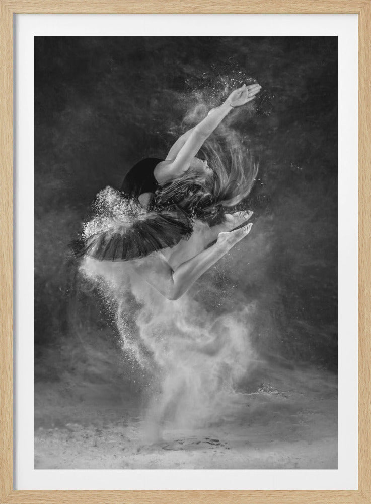 A dramatic black and white photograph of a ballerina in mid-air, captured in a graceful leap. She is wearing a black leotard and tutu, and an explosion of white powder surrounds her, creating a cloud-like effect against a dark, moody background. Her arms are raised above her head, her back is arched, and her hair is flowing, conveying a sense of dynamic movement and elegance. Decor
