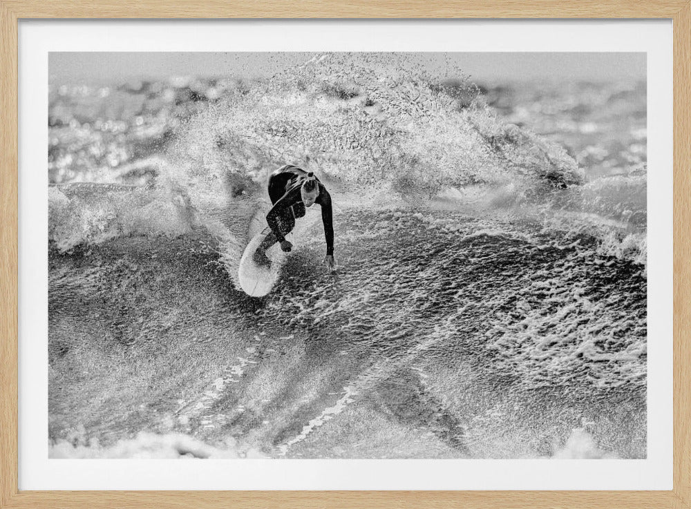 A dramatic, high-contrast black and white photograph of a surfer carving a turn on a large wave. The surfer, wearing a dark wetsuit, leans into the turn, sending a massive spray of white water into the air, showcasing the power and energy of the ocean. Wall Art