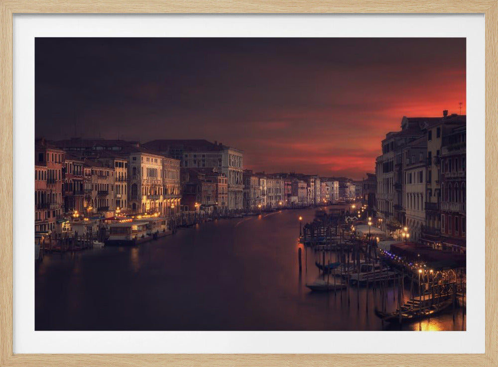 A framed photograph of the Grand Canal in Venice at dusk. A dramatic red and orange sky hangs over the historic, illuminated buildings that line the waterway, their lights reflecting in the dark water. Wall Art