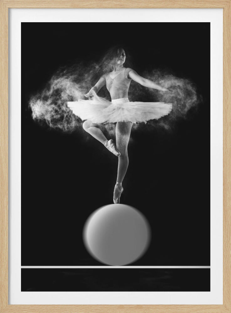 A dramatic black and white photograph of a ballerina balancing on one pointe shoe on top of a large sphere. She wears a white tutu and is surrounded by a cloud of white powder, capturing a moment of explosive, graceful movement against a solid black background. Wall Art