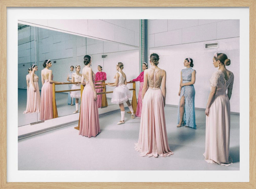 A group of ballerinas in a dance studio, wearing a mix of elegant pink and blue evening gowns and traditional ballet wear, stand gracefully around a barre in front of a large mirror that reflects the serene scene. Decor