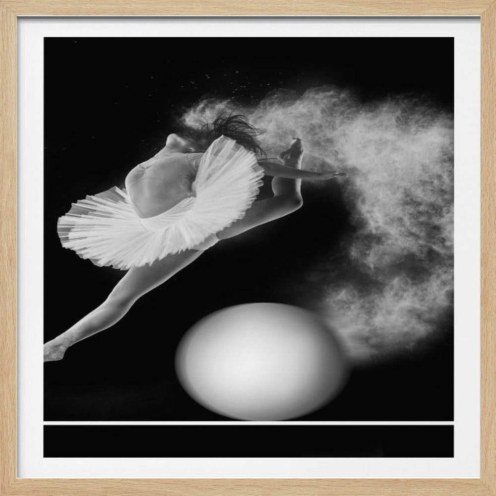 A dramatic black and white photograph of a ballerina in a white tutu, captured mid-leap. She is arching her back gracefully as a cloud of white powder explodes around her, creating a sense of dynamic motion. Below her, a large white sphere rests on a thin white line against the stark black background. The artwork is presented in a light wood frame. Print