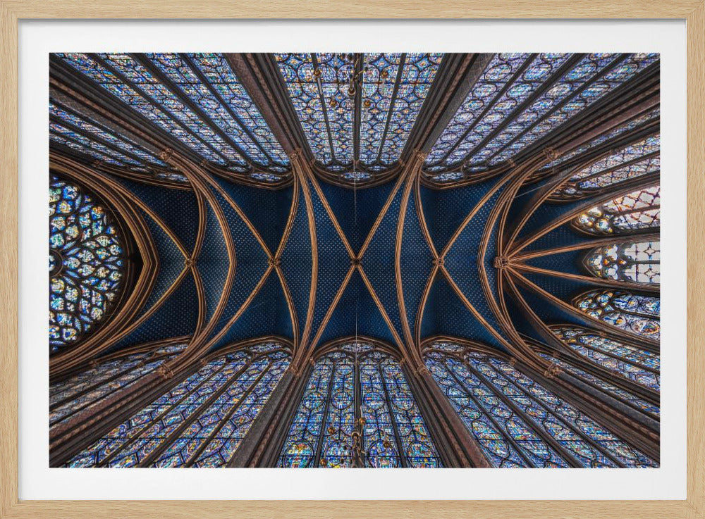 A symmetrical, upward-looking photograph of the ornate vaulted ceiling of a Gothic cathedral, featuring a deep blue, star-patterned ceiling with golden ribs, surrounded by towering, intricate stained-glass windows, all enclosed in a silver frame. Decor