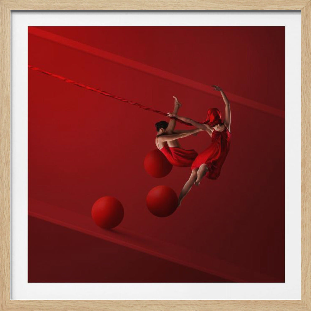A surreal piece of art with a solid red background featuring two dancers in red dresses. They appear to float in the air, interacting with each other, a long red ribbon, and three large red spheres, creating a dynamic and gravity-defying scene, all enclosed in a light wood frame. Wall Art