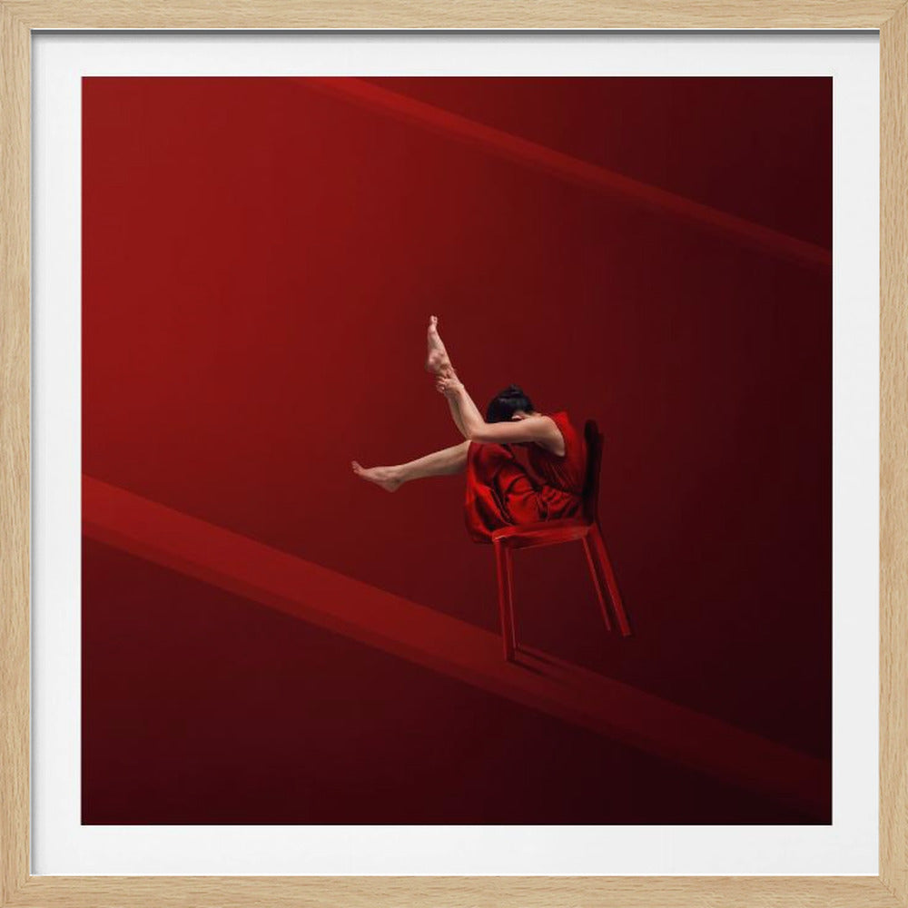 A minimalist, framed photograph featuring a woman in a red dress sitting on a red chair against a solid red background. She is in a highly flexible pose, holding her foot high above her head with both hands. The scene is illuminated in a way that creates subtle diagonal bands of light and shadow. Poster