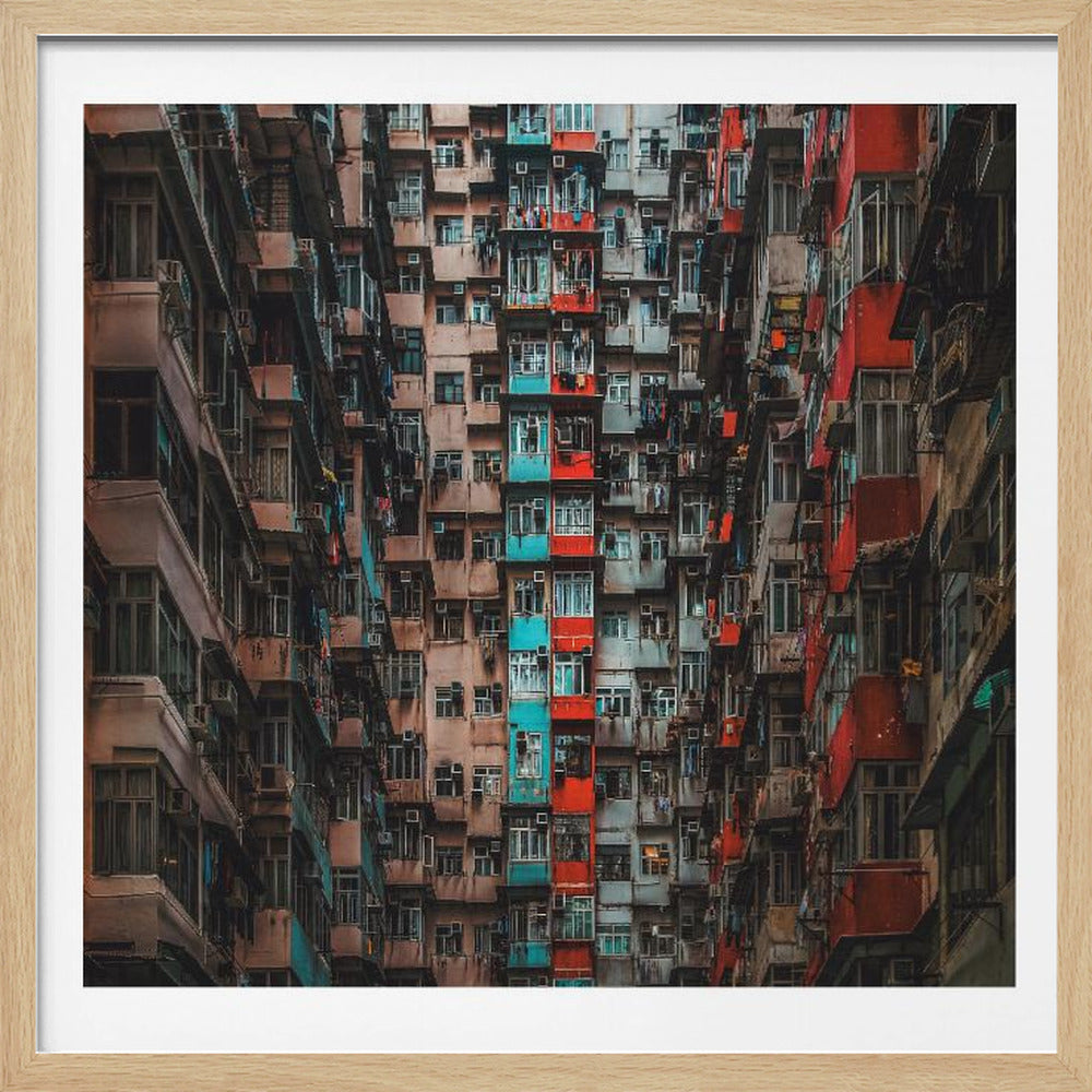 A framed, low-angle photograph looking up at densely packed, weathered apartment buildings that create a canyon-like view, with some facades painted in vibrant red and teal. Wall Art