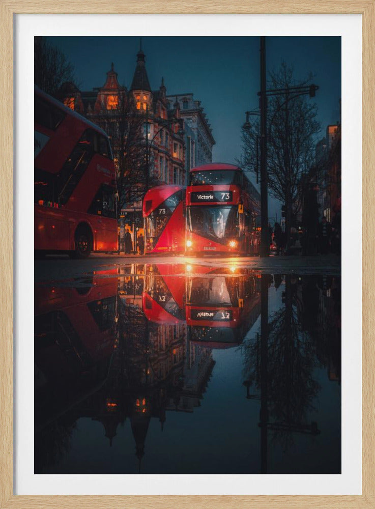 A moody, low-angle photograph of a wet London street at dusk, with a vibrant red double-decker bus reflected perfectly in a large puddle in the foreground. Print