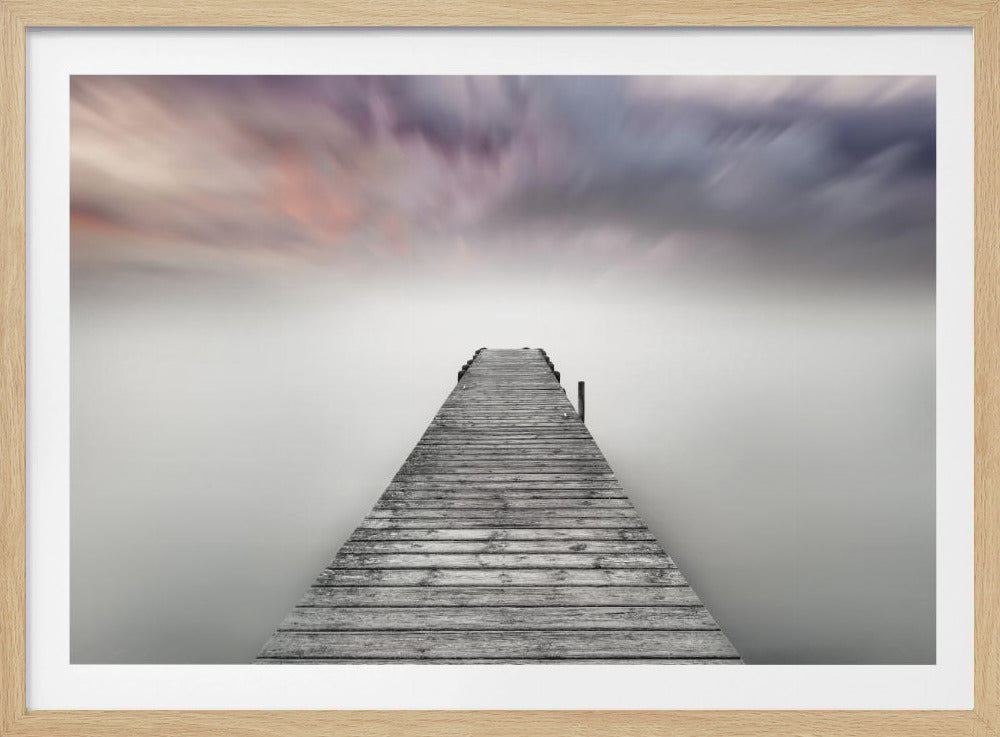 A long exposure photograph of a weathered wooden pier extending into a still, misty lake under a dramatic, motion-blurred sky of purple, pink, and grey, creating a serene and ethereal atmosphere. The artwork is displayed in a silver frame. Print