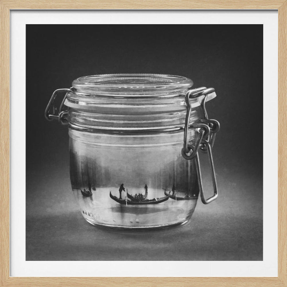 A surreal black and white photograph of a glass canning jar containing a miniature scene of Venice. Inside the jar, several gondolas float on water against a hazy cityscape background. The photo is displayed in a light wood frame. Poster