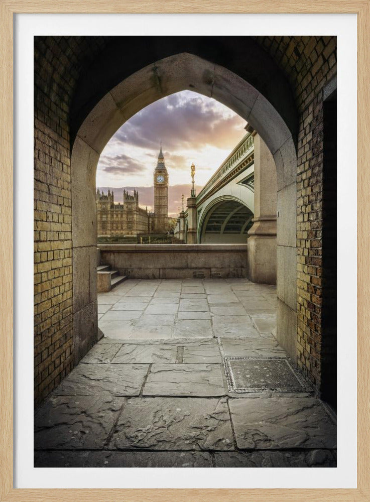A scenic view of London's Big Ben clock tower and the Houses of Parliament as seen through a weathered stone archway. The foreground features a stone-paved walkway, and the background shows the iconic landmarks against a cloudy sunset sky with hues of purple and orange. Poster