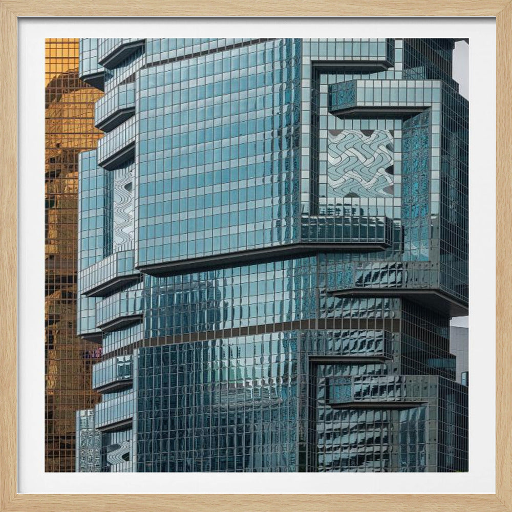 A framed close-up photograph of modern architecture, featuring a golden grid-patterned skyscraper next to a complex blue glass building with jutting levels and distorted reflections. Wall Art