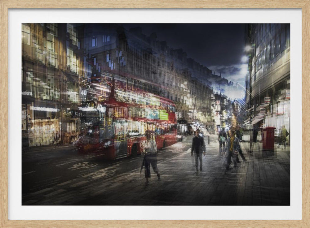 A long-exposure, artistic photograph of a busy London street at night. The motion of a red double-decker bus and pedestrians creates a blurred, ghost-like effect, capturing the vibrant energy of the city. The scene is illuminated by streetlights and building windows, all set within a silver frame. Artwork