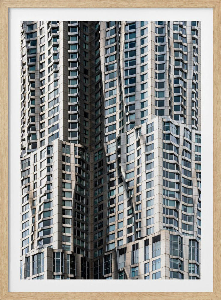 A close-up photograph of the facade of a modern skyscraper with an undulating, wave-like metallic exterior. The building is filled with windows that reflect the light, creating a dynamic pattern of highlights and shadows, all captured within a black frame. Print