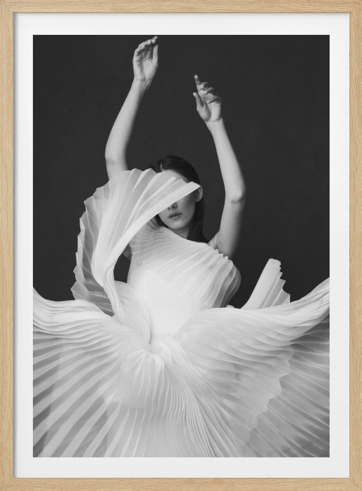 A striking black and white portrait of a woman in a dramatic, pleated white dress. Her arms are raised elegantly above her head, and a fan-like part of the dress partially covers her face, leaving only her mouth and chin visible. The voluminous dress flows around her against a dark, plain background. Poster