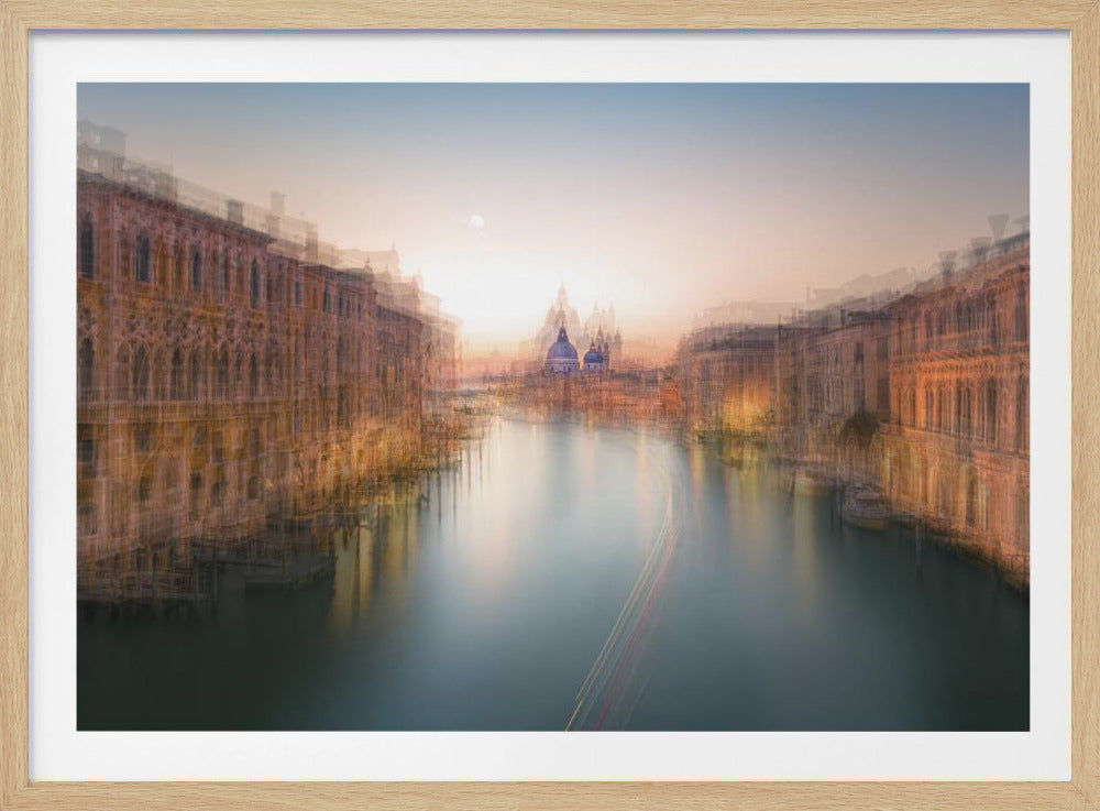 An abstract, dreamlike photograph of the Grand Canal in Venice at sunset, presented in a silver frame. The image uses a multiple exposure or motion blur effect, causing the historic buildings on both sides of the canal to appear as ghostly, layered impressions. The water is smooth with long light trails from a boat, and in the distance, the Santa Maria della Salute basilica is silhouetted against a soft orange and blue sky. Wall Art