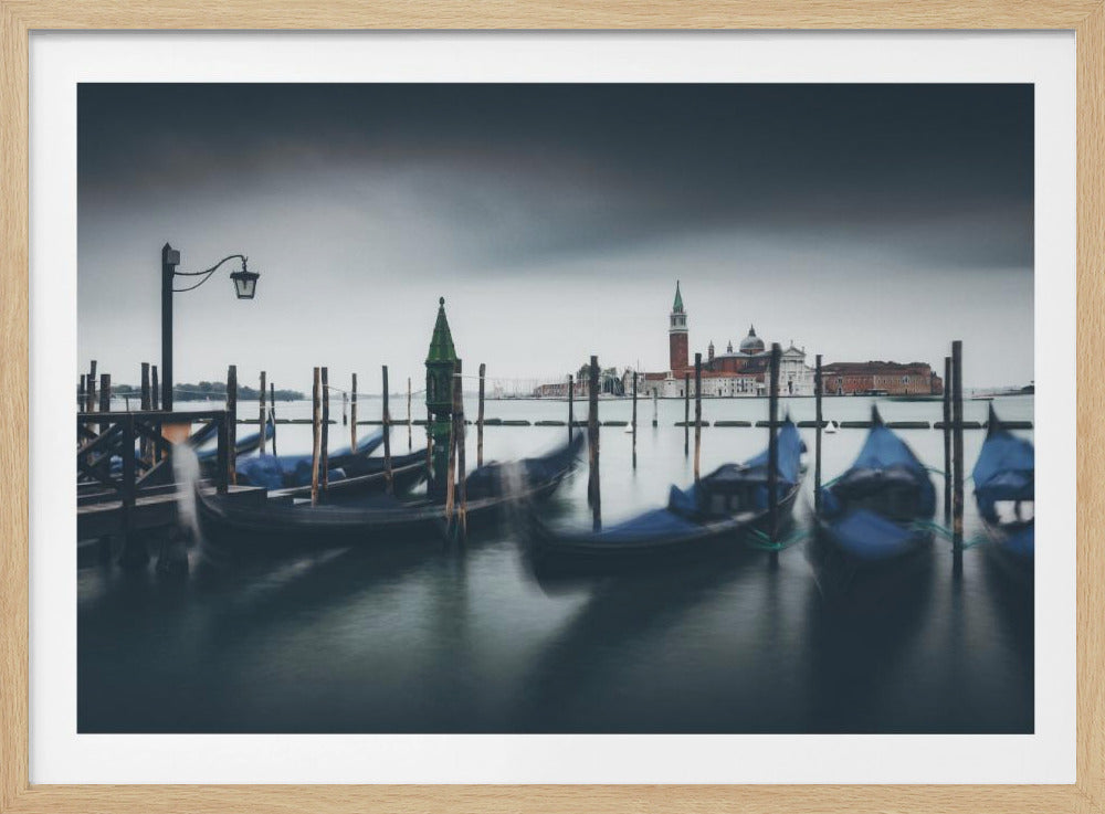 A moody, long-exposure photograph of gondolas bobbing in a Venetian canal, with the island of San Giorgio Maggiore visible in the background under a dark, stormy sky. The image is presented in a silver frame. Poster
