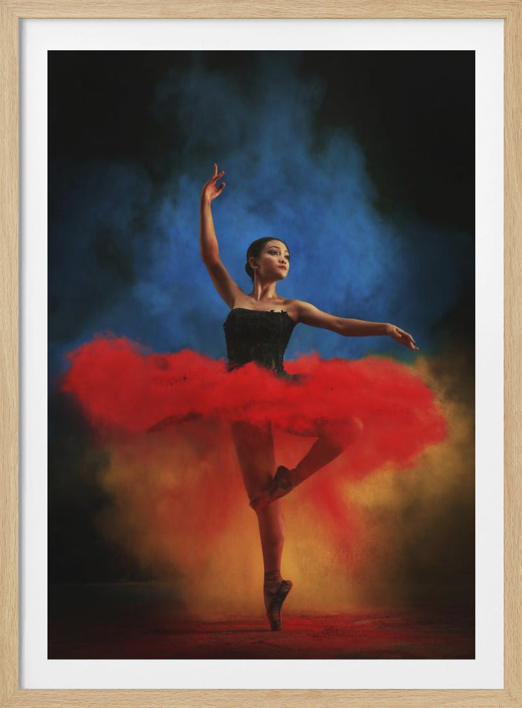 A ballerina in a black leotard and a vibrant red tutu made of colored powder strikes a graceful pose against a backdrop of blue and yellow smoke. Print