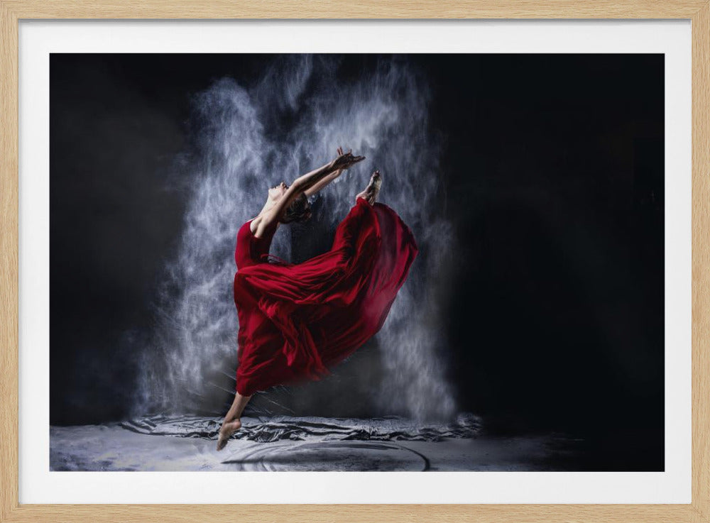 A graceful female dancer in a vibrant red, flowing dress is captured mid-leap, suspended in the air. She is surrounded by a dramatic cloud of white powder against a stark black background, creating a powerful and artistic contrast. The entire scene is presented within a silver frame. Wall Art