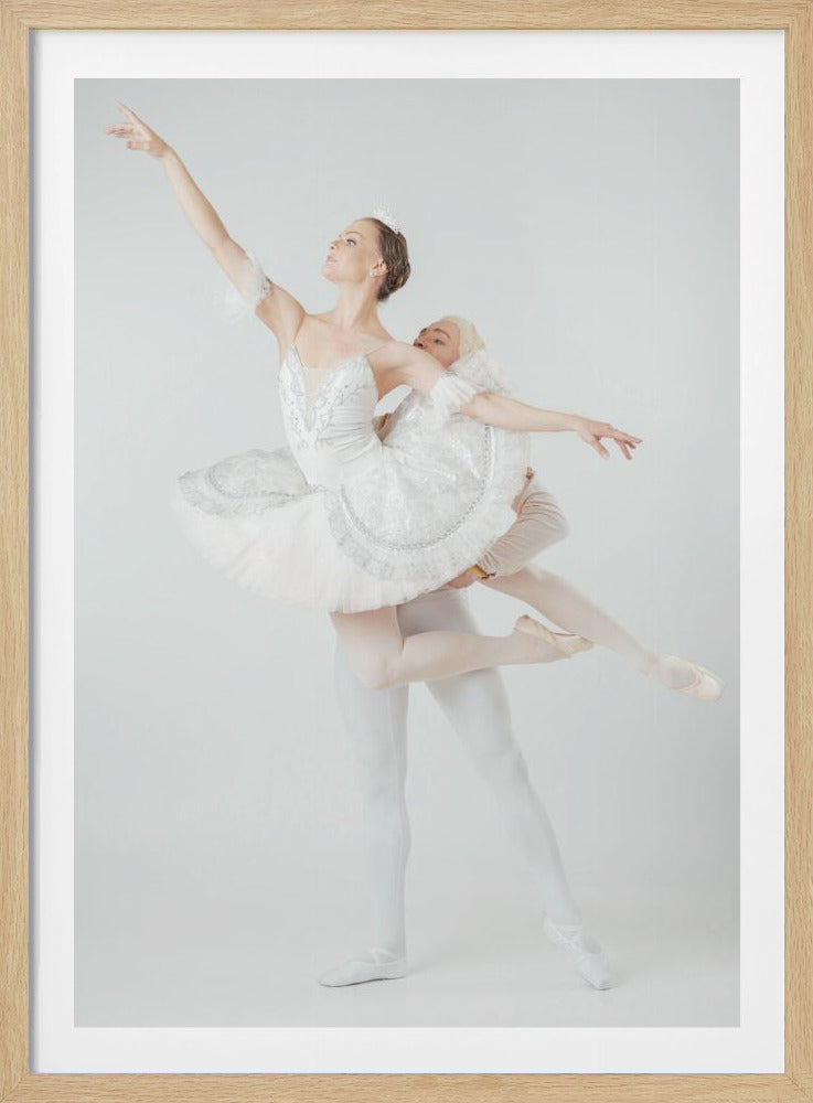 A male ballet dancer in white tights lifts a ballerina wearing a white tutu and tiara as she strikes a graceful pose with one arm extended towards the sky, against a solid white background. Artwork
