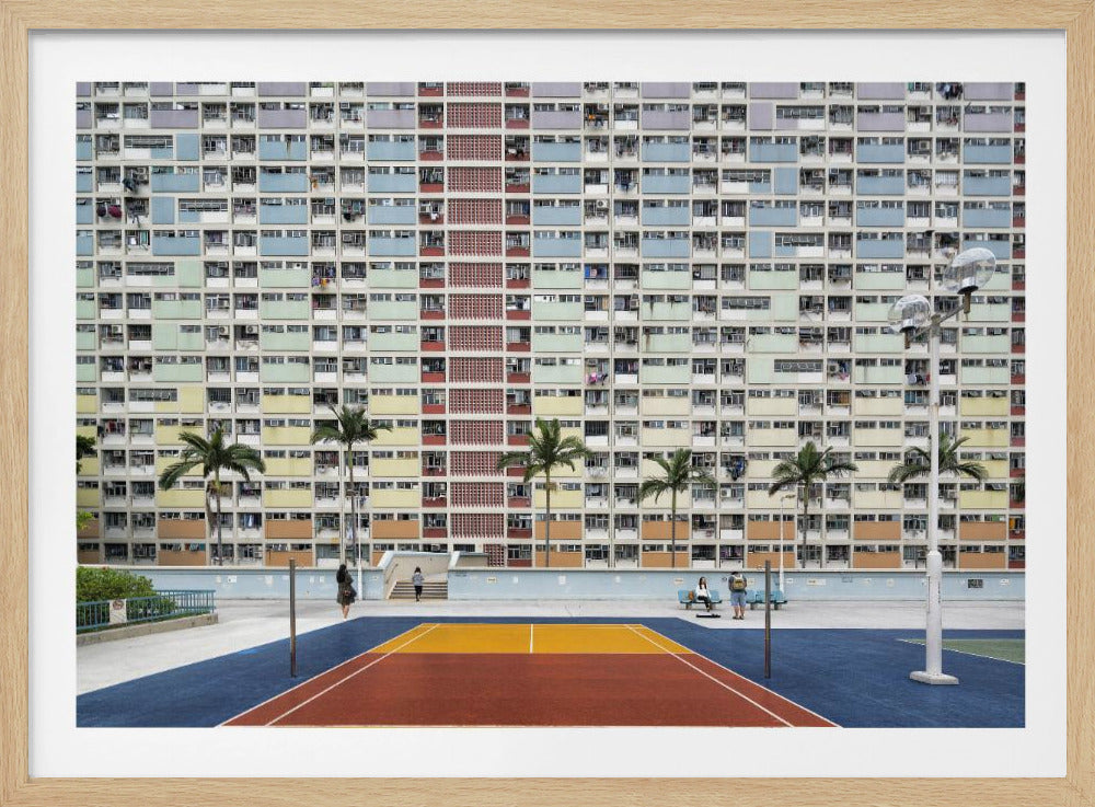 A wide, symmetrical photograph of the colorful Choi Hung Estate apartment building in Hong Kong, featuring a facade with a repeating pattern of pastel blue, green, yellow, and orange blocks. In front of the building is a vibrant basketball court painted in bold sections of blue, red, and yellow, with several palm trees lining the courtyard. Print