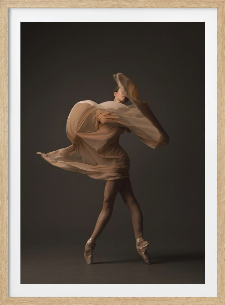 A full-length studio photograph of a ballerina dancing en pointe, wrapped in a large, flowing piece of light beige fabric that swirls around her body, partially obscuring her face. The scene is set against a solid dark gray background, creating a dramatic and artistic effect of motion and grace. Artwork